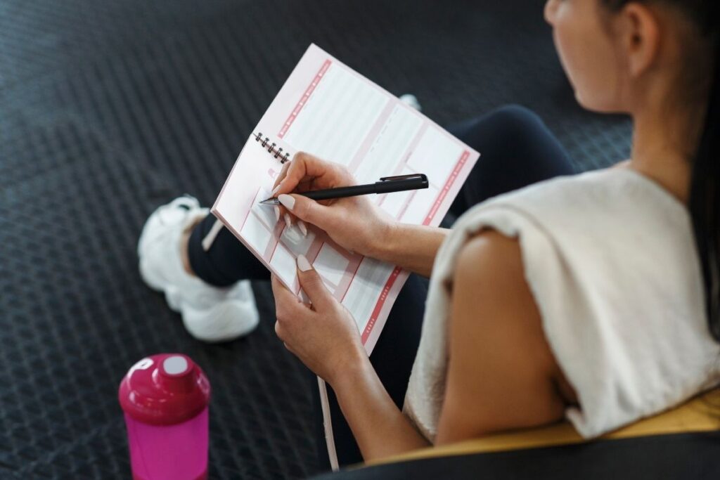 Retrouver la motivation après les fêtes : Objectifs de remise en forme écrits dans un carnet.